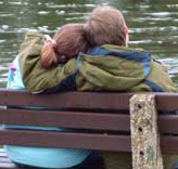 a couple on a bench in fron of a lake